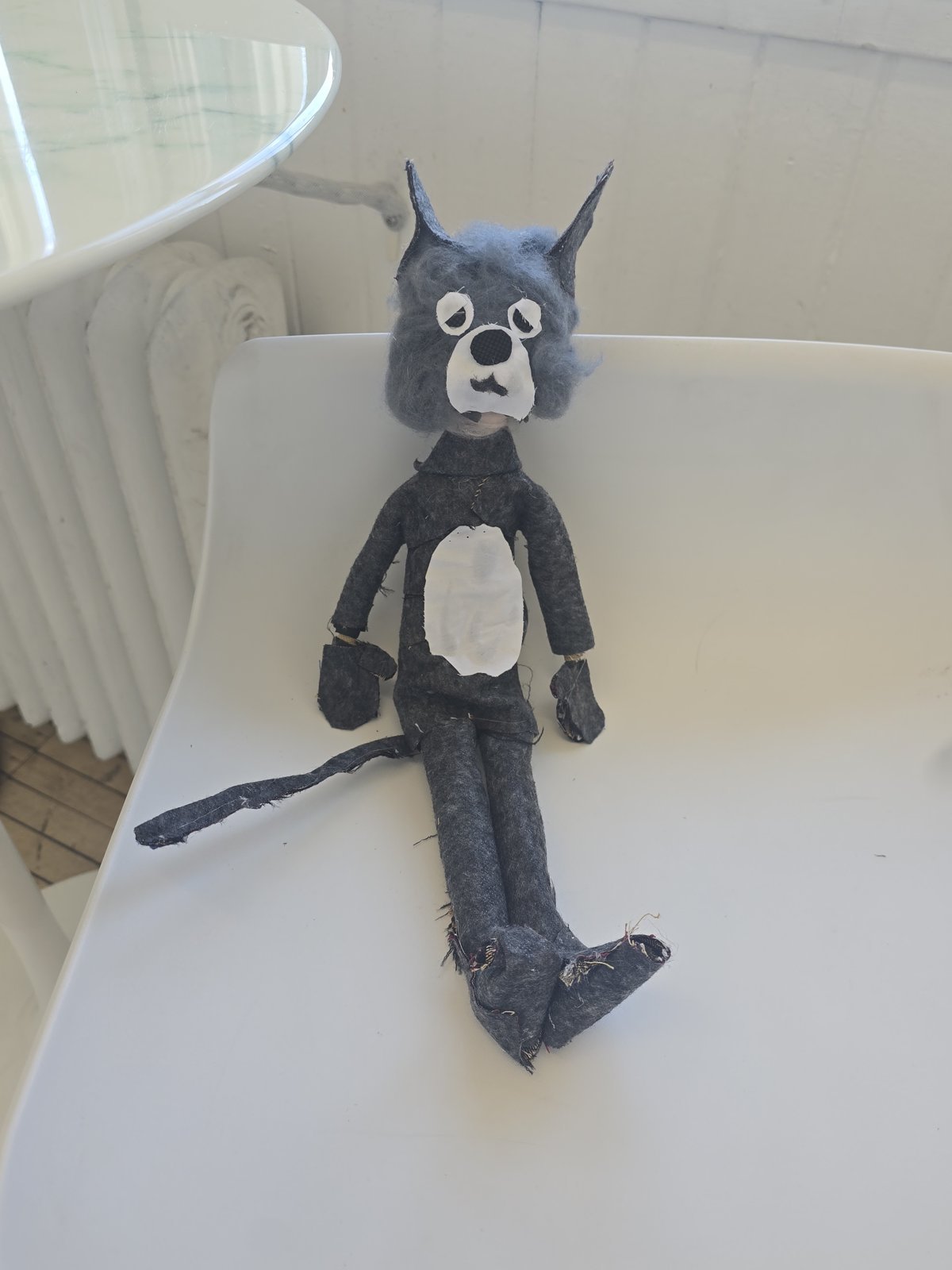 The finished grey felt mouse puppet with pointed ears and a long tail